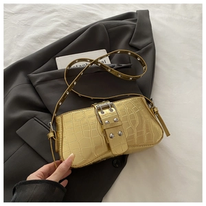 Close-up of metallic gold crocodile texture handbag with silver eyelets on strap