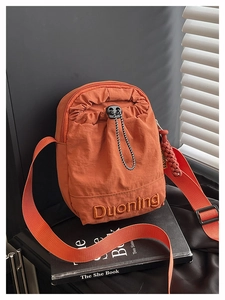 Vue détaillée du petit sac bandoulière orange en nylon avec broderie et cordon