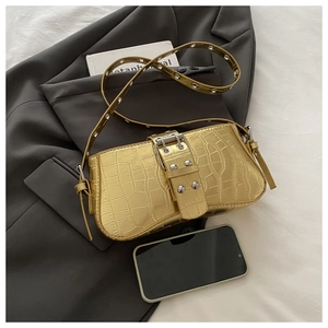Close-up of golden crocodile pattern bag with metallic luster and silver rivet strap details