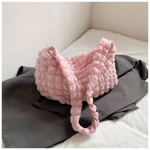 Close-up of pink pleated puff shoulder bag with cloud-like texture on a grey blazer