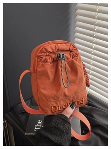 Detail of orange nylon crossbody bag with drawstring closure and embroidered logo