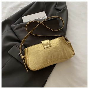 Detail of gold crocodile embossed leather shoulder bag with metallic eyelet strap