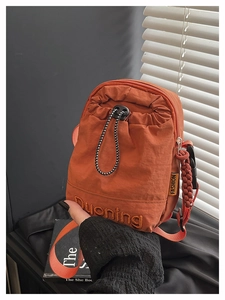 Détail du mini sac bandoulière orange en nylon avec cordon de serrage et broderie Quoning