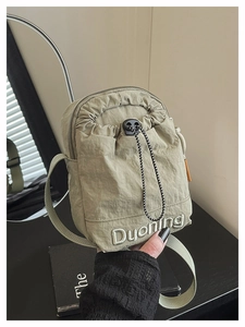 Detail of green nylon crossbody phone bag with drawstring closure and white embroidery