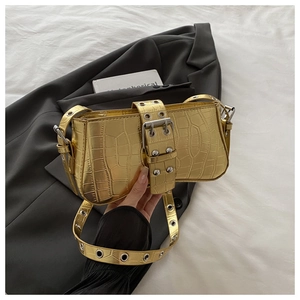 Macro detail of golden crocodile pattern shoulder bag with rivet buckle strap and metallic finish
