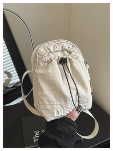 Detail of off-white nylon crossbody bag with drawstring closure and white embroidery