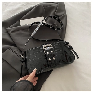 Macro view of black crocodile pattern leather bag with silver metal eyelet strap detail