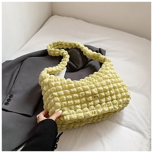 Detail of the pale yellow popcorn texture fabric on a stylish ruched tote bag surface