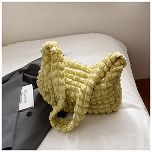 Detail of light yellow plissé bubble textured fabric on a stylish ruched tote bag
