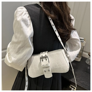 Close-up of white crocodile pattern shoulder bag with a metallic buckle and luxury texture