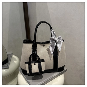 Detail of canvas tote bag with black leather trim, metal buckle and floral scarf