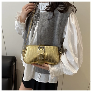 Close-up of gold crocodile-embossed shoulder bag with a stylish metal buckle design