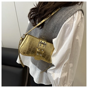 Detail of metallic gold crocodile pattern shoulder bag with rivet eyelets on the strap
