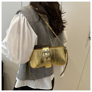 Detail of gold crocodile embossed shoulder bag with y2k buckle and metallic strap eyelets