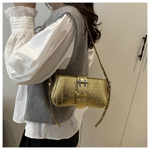 Close-up of gold crocodile-patterned baguette bag with metallic texture and buckle detail