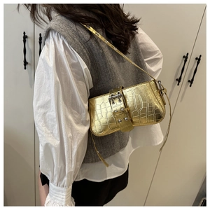 Detail of gold crocodile embossed baguette bag with silver buckle and stud hardware