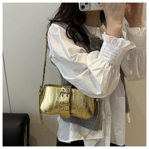 Metallic gold croc-embossed baguette bag with oversized silver buckle on a shoulder strap