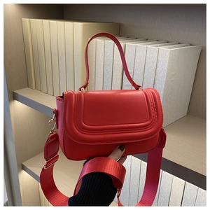 Detail of red matte leather square bag with U-shaped stitching and wide textile strap