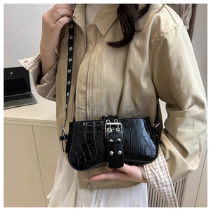 Detail of black crocodile embossed patent leather handbag with silver buckle and eyelets