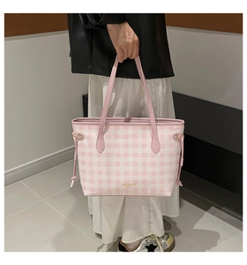 Detail of a pink and white gingham tote bag with brand lettering held by a model
