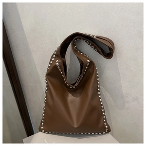 Close-up of brown shoulder bag featuring silver round rivets on edges and strap
