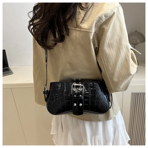 Detail of black crocodile embossed patent leather handbag with silver metallic buckle