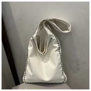 Detailed view of cream-colored shoulder bag with silver rivet trim and soft PU leather