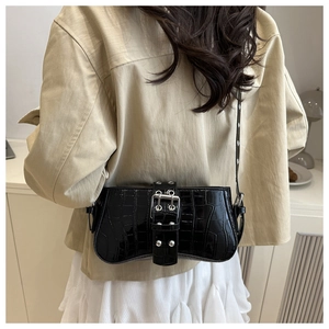 Detail of black crocodile pattern shoulder bag with silver buckle and rivets on the strap