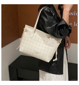 Close-up of cream plaid tote bag featuring side drawstring detail and long shoulder straps