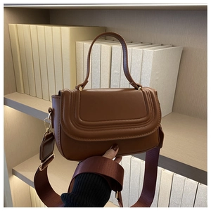 Detailed view of the brown leather crossbody bag with elegant gold hardware and strap