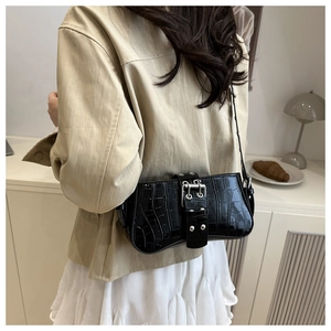 Macro shot of black crocodile embossed baguette bag with a bold silver metal buckle