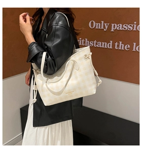 Detail of checkered tote bag with drawstring accents and brand text for autumn fashion