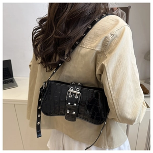 Detail of black crocodile pattern shoulder bag with silver rivets and metal buckle