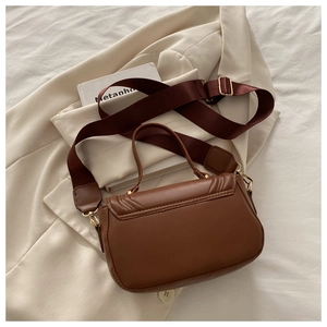 Detail of caramel leather crossbody bag with V-quilted texture and wide nylon strap