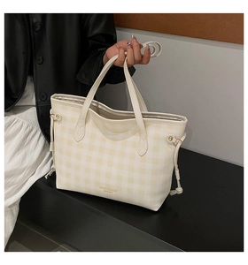 Close-up of checkered tote bag with drawstring tassel and golden logo lettering detail