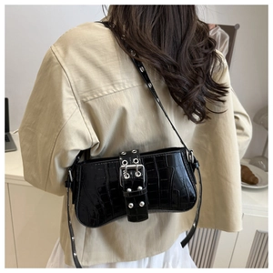 Detail of black glossy crocodile pattern shoulder bag with silver buckle and studs