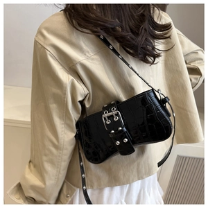Close-up of black crocodile pattern patent leather shoulder bag with silver rivet details