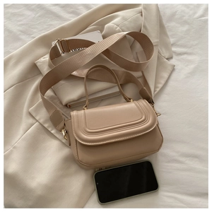 Detailed view of beige crossbody bag capacity showing size comparison with a smartphone