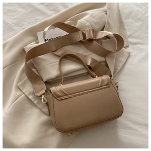 Detail of beige PU leather crossbody bag with wide strap and gold hardware accents