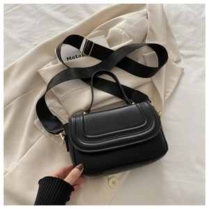 Detail of black crossbody square bag with three-layer quilted lines and gold hardware