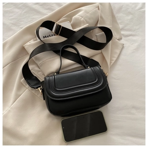 Macro shot of minimalist black crossbody bag showing three-layer stitching and metal buckles