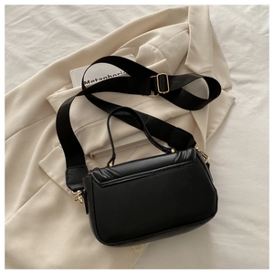 Detail of the black leather shoulder bag with wide fabric strap and golden hardware