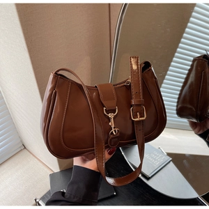 Détail d'un sac porté épaule marron brillant avec boucle métallique et sangle réglable