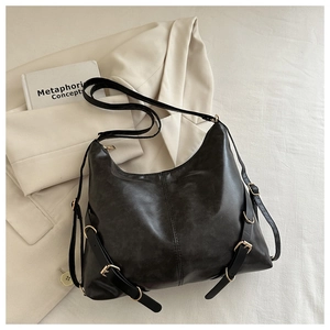 Détail du sac cabas en cuir mat noir avec boucle dorée posé sur un blazer beige