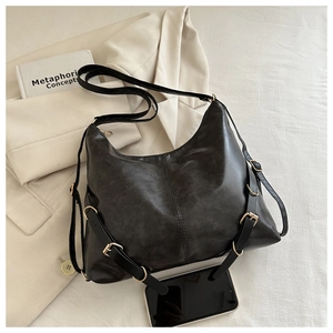 Détail du sac hobo en cuir noir avec boucles métalliques et smartphone pour l'échelle