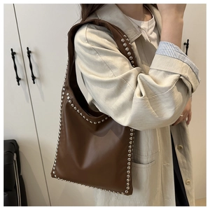 Close-up of brown faux leather shoulder bag with vintage silver metal rivet detailing