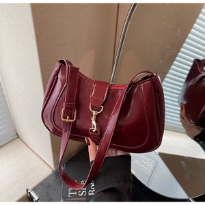 Détail de la texture en cuir verni bordeaux brillant avec boucle métallique dorée