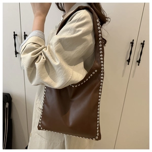 Close-up of brown PU leather tote bag with silver rivet details on the shoulder straps