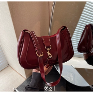 Détail du sac baguette en cuir verni rouge foncé avec boucle en métal doré élégante