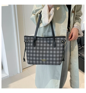 Detail of grey checkered tote bag with black straps and side drawstring on model